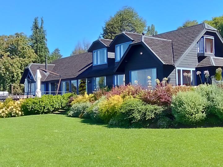 Jardín con macizos de arbustos frente a una casa