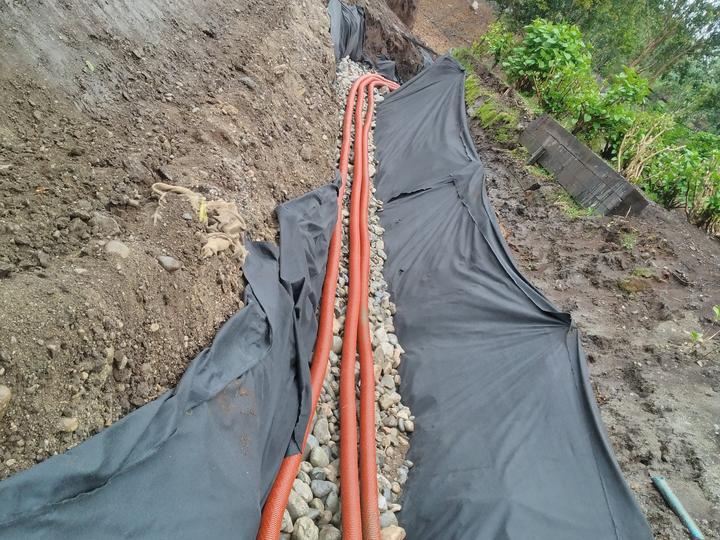 Drenaje con geotextil, bolón y tuberías en un talud